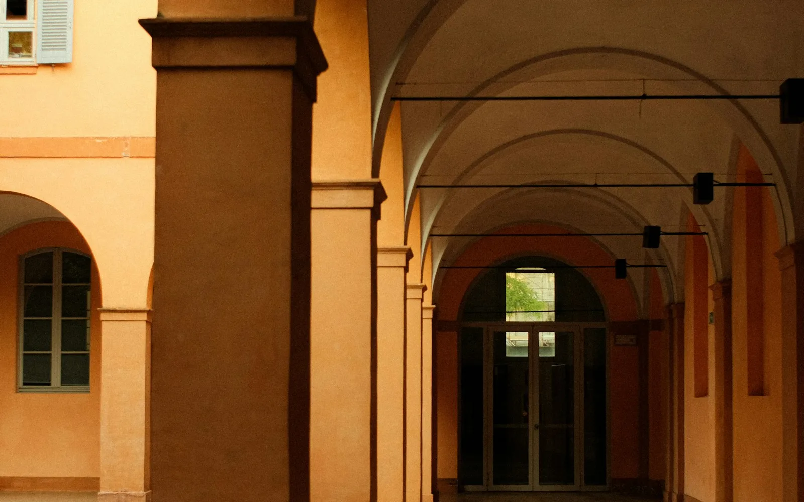 Portico voltato di un edificio italiano che conduce a un portone vetrato interno.