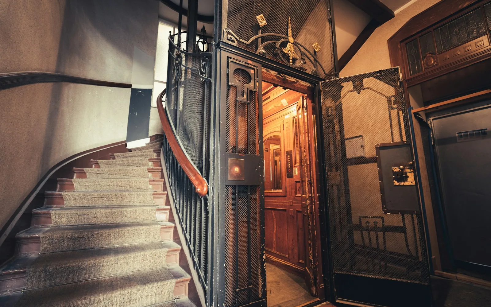 Ascensore d'epoca con cabina in legno e gabbia in ferro nel vano scala di un palazzo a Milano.