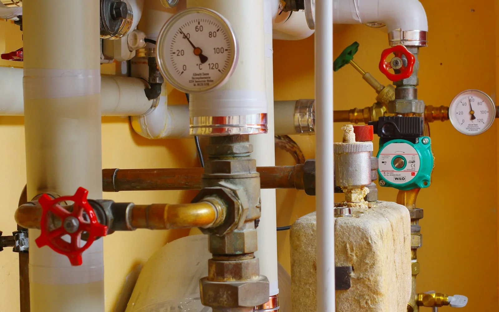 Centrale termica condominiale con tubazioni, manometri e pompe di circolazione.