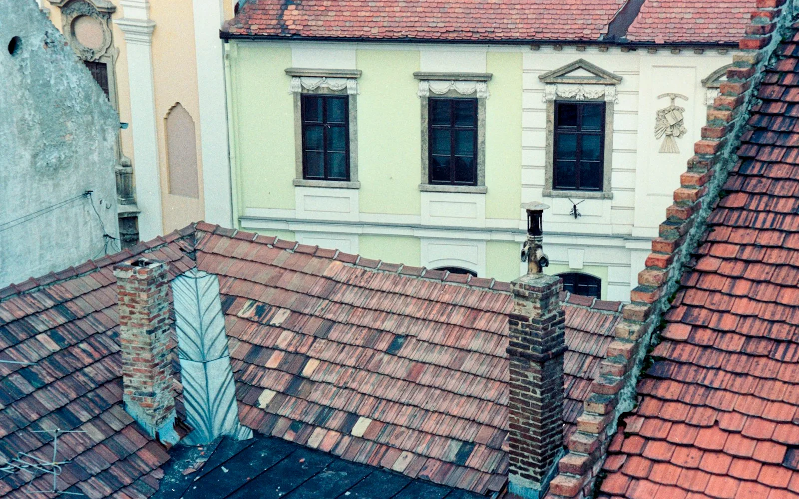 Tetti in coppi di edifici residenziali con comignoli in mattoni e uno scarico fumi.