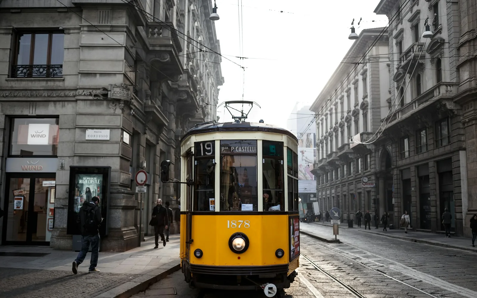 Tram giallo milanese in una via fiancheggiata da palazzi residenziali.