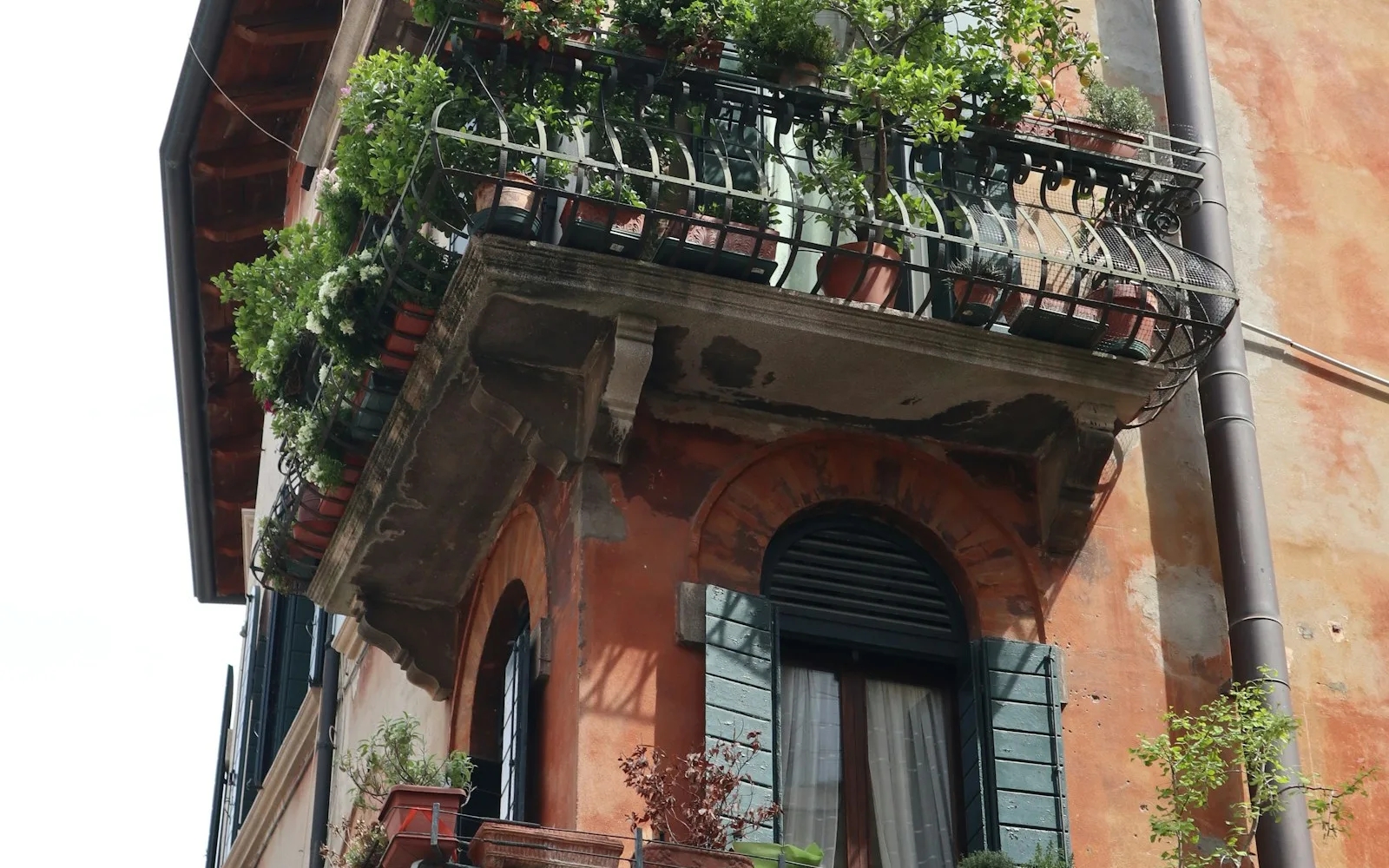 Angolo di un palazzo italiano con balconi in ferro battuto e intonaco color terracotta.