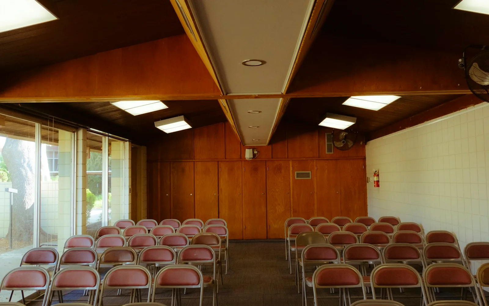 File di sedie vuote in una sala riunioni con pareti in legno, senza nessuno.