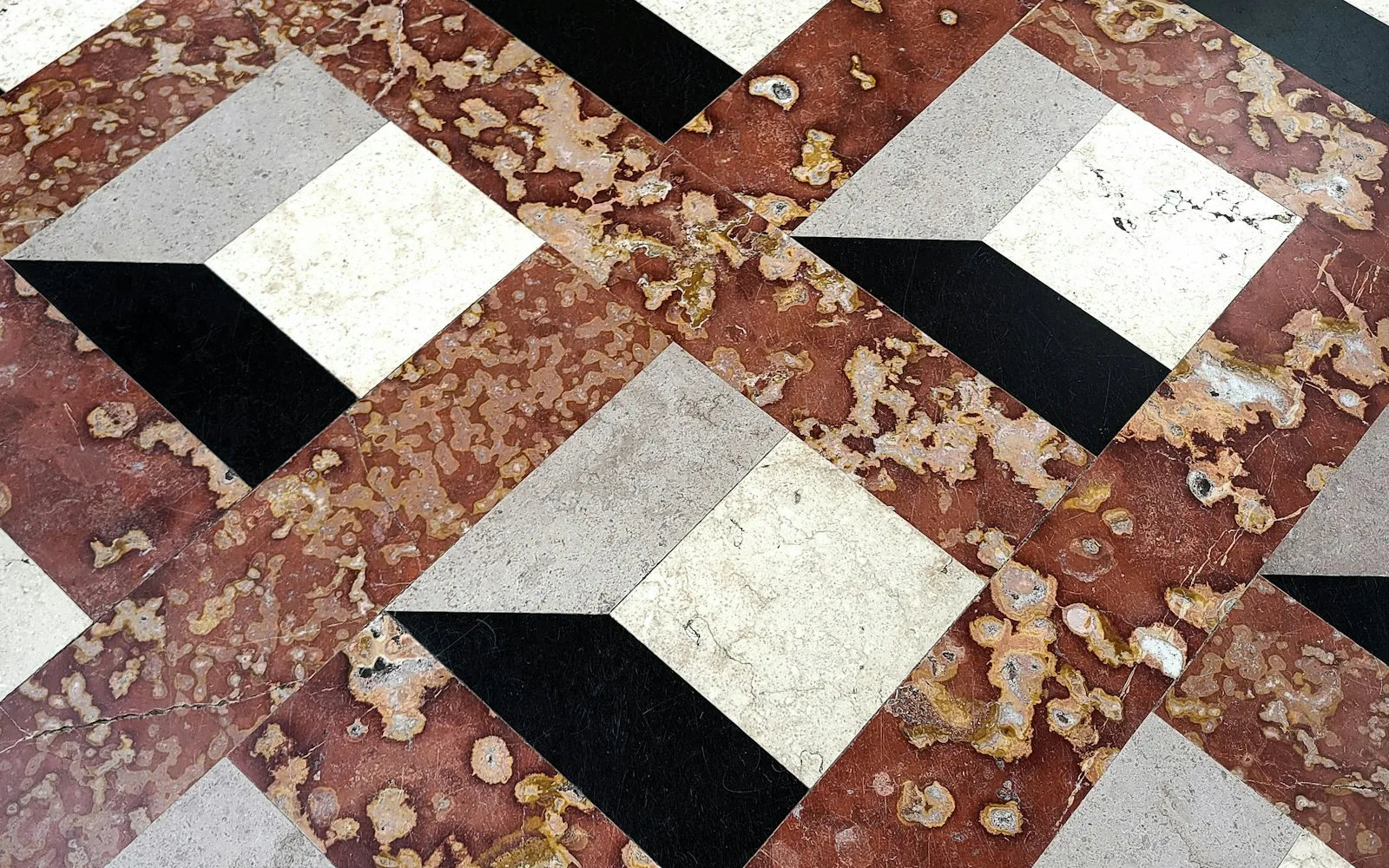 Pavimento in marmo intarsiato dell'atrio di un palazzo, lucido e geometrico, visto dall'alto.