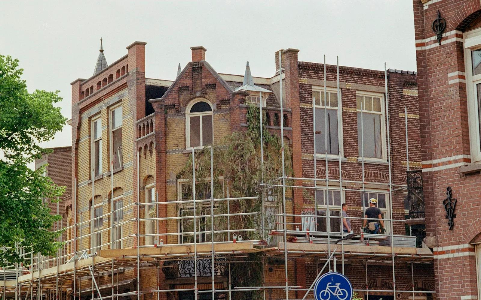 Facciata di un edificio residenziale europeo in ristrutturazione, con ponteggio e operai al lavoro.