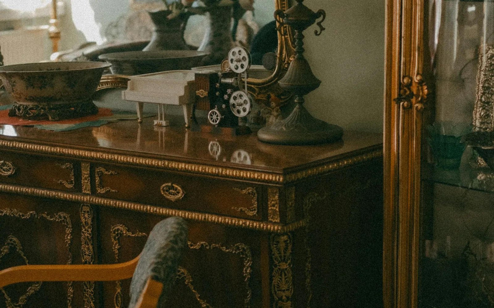 Interno di un vecchio appartamento italiano con specchiera dorata, comò intarsiato e vetrina.