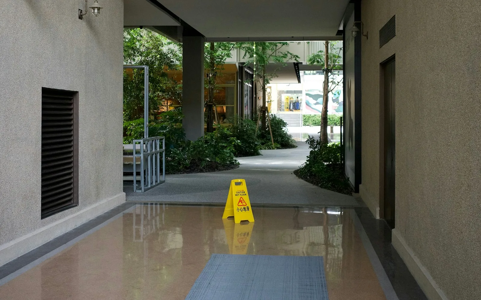 Cartello giallo di pavimento bagnato in un passaggio coperto condominiale.