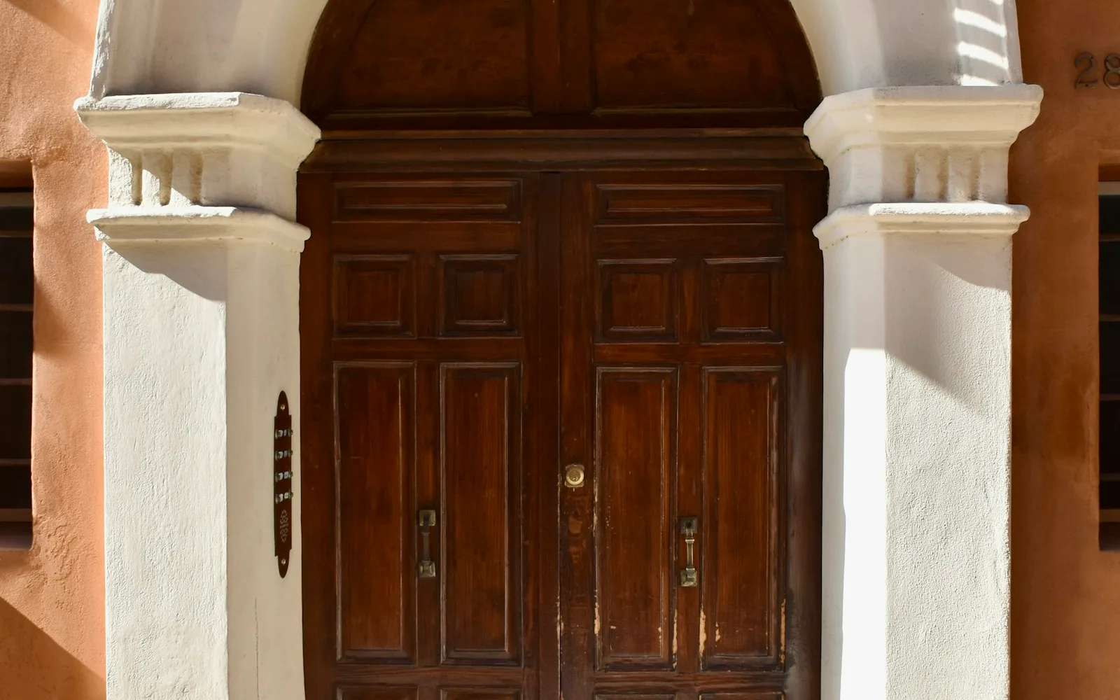 Portone d'ingresso di un palazzo a Ferrara con la pulsantiera dei citofoni e i nomi accanto allo stipite.