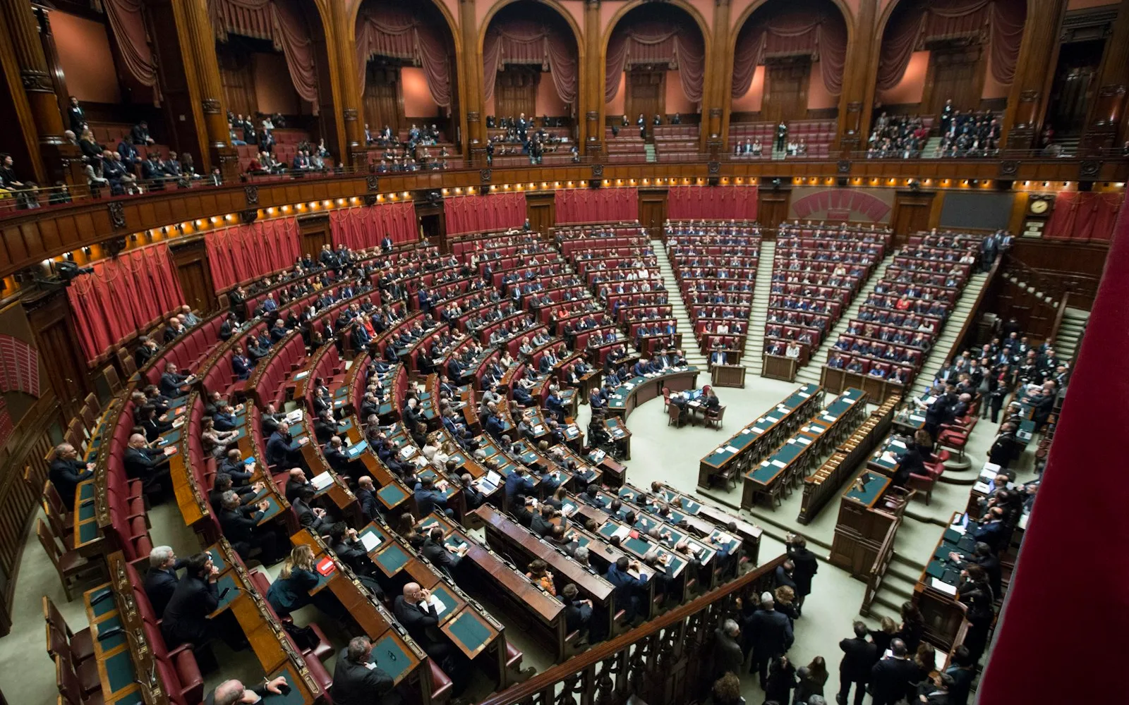 Aula della Camera dei deputati a Roma vista dall'alto, con gli scranni rossi occupati durante una seduta.