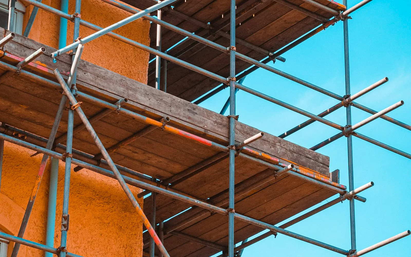 Ponteggio montato sulla facciata intonacata di un edificio residenziale.