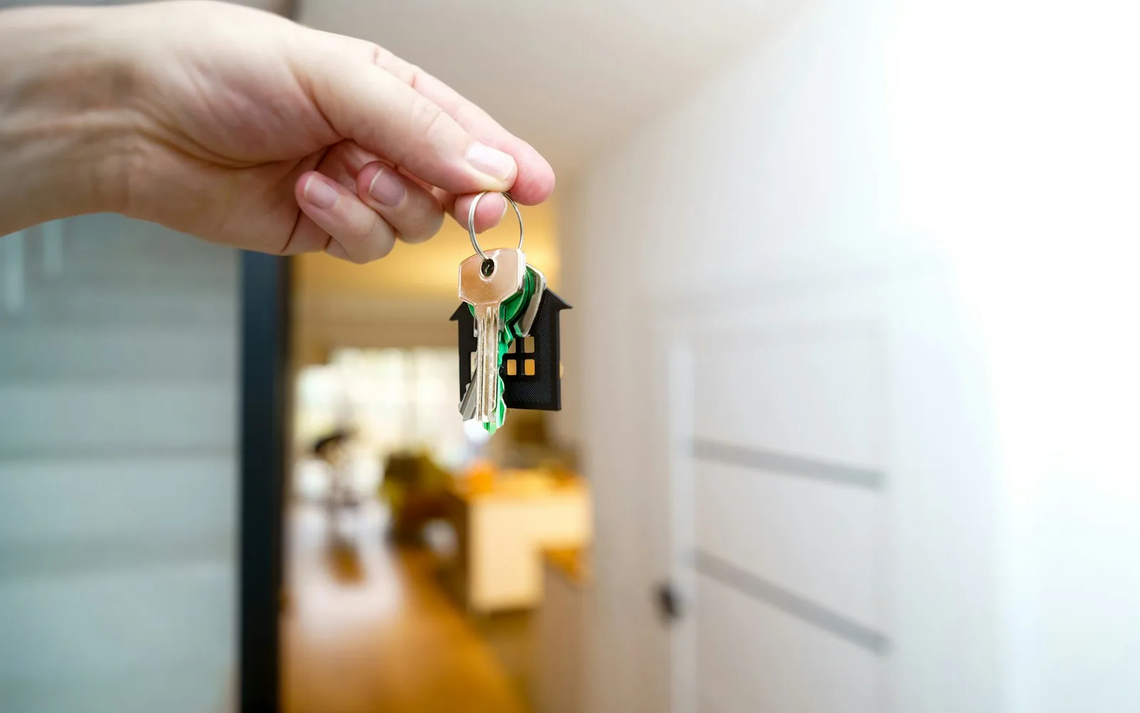 Chiavi di casa con portachiavi tenute in mano nell'ingresso di un appartamento.