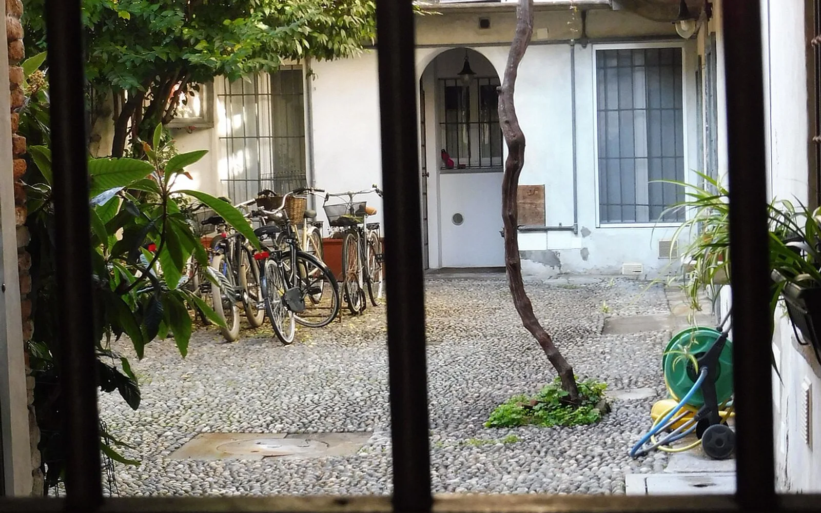 Cortile interno di un palazzo residenziale a Milano, con pavimentazione a ciottoli e biciclette.