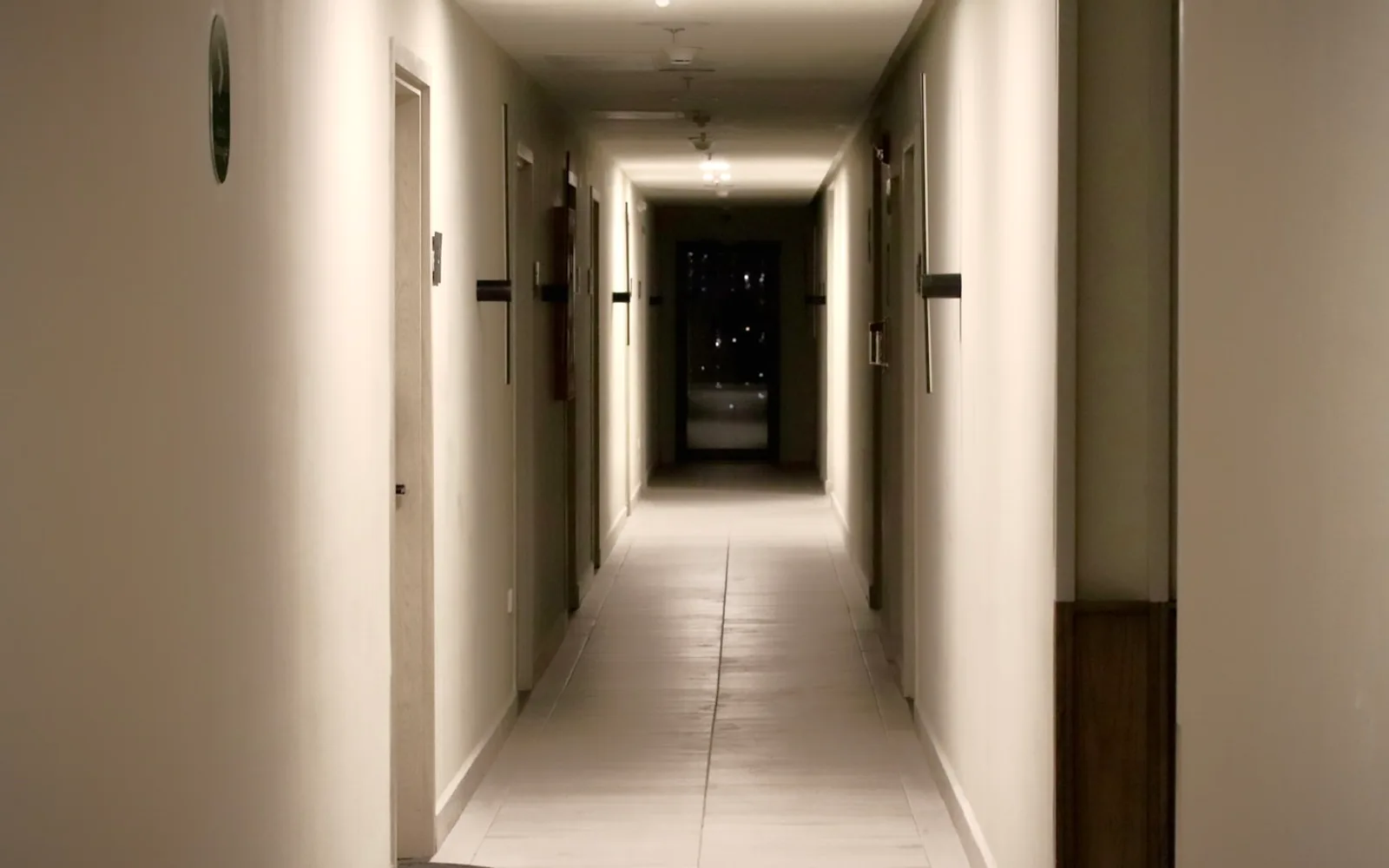 Corridoio condominiale poco illuminato con porte degli appartamenti su entrambi i lati.
