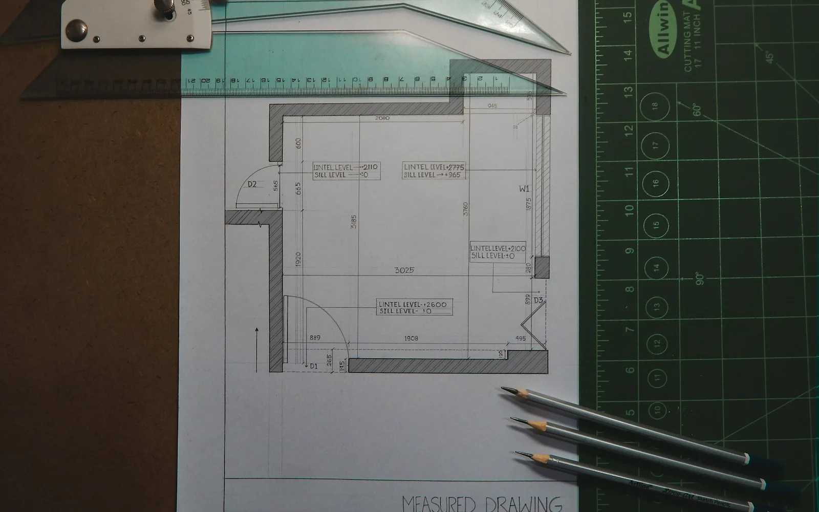 Planimetria di un appartamento su un tavolo da disegno con squadra e matite.
