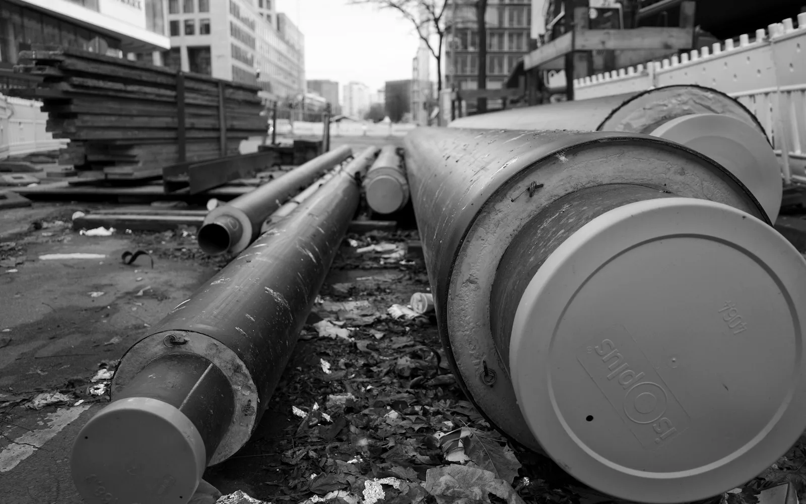 Grandi tubazioni preisolate per teleriscaldamento posate lungo una strada cittadina.